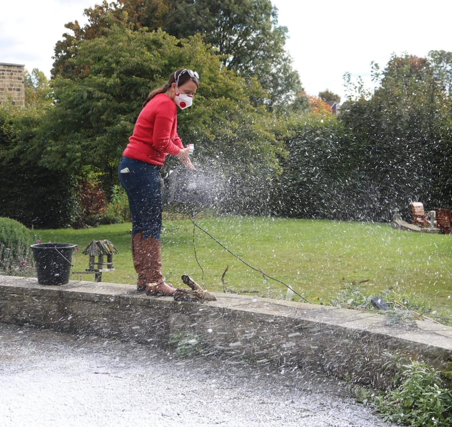 Member of staff at Bluebell Wood Children’s Hospice sprays fake snow on the grass at the hospice.