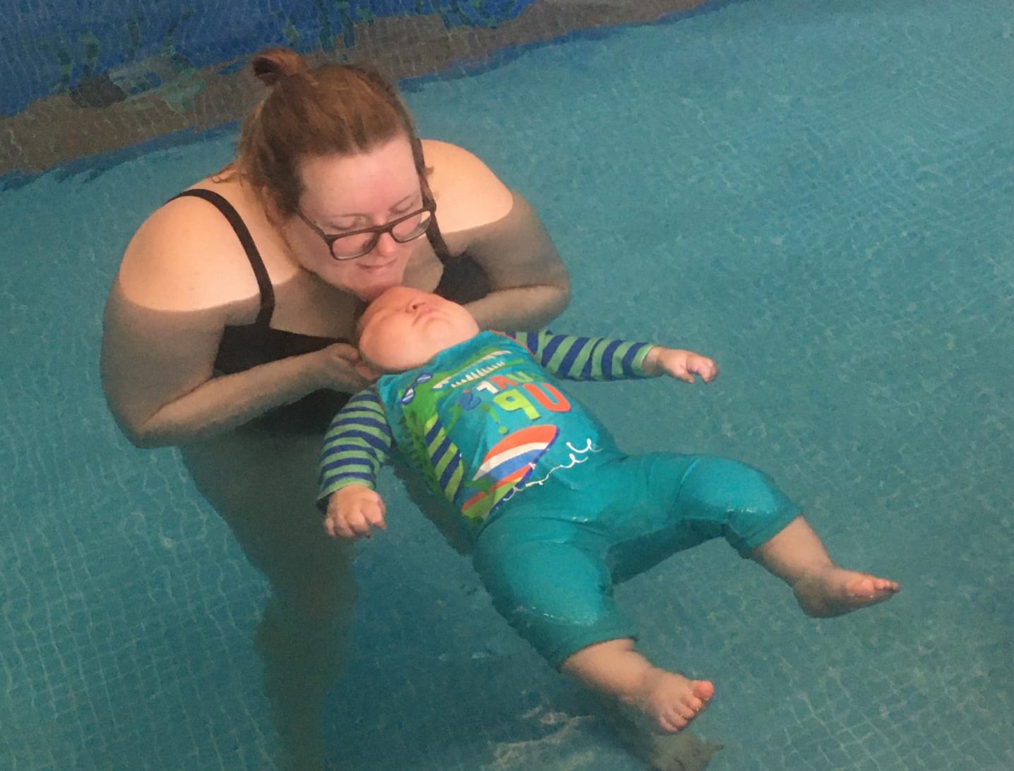 Mum Natasha holds her son, Elijah, while he floats in a swimming pool.